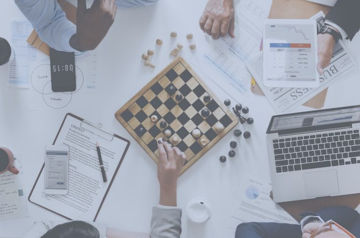 Simülasyonlu stratejik düşünme eğitimi, satranç tahtası üzerinde stratejik hamleler yapan iş profesyonelleriyle görselleştirilmiştir.